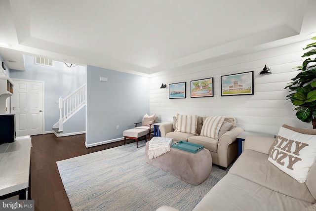 living room with a raised ceiling and dark hardwood / wood-style flooring