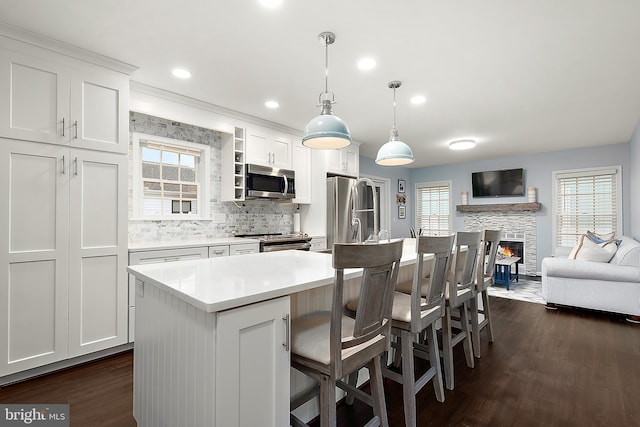 kitchen featuring white cabinets, pendant lighting, a kitchen island, and a stone fireplace