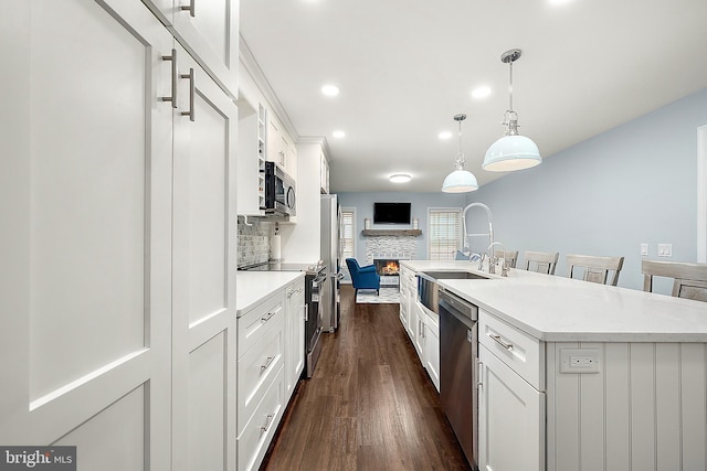 13801 Fountain Rd, Ocean City, MD 21842 - kitchen featuring appliances with stainless steel finishes, a sink, a fireplace, dark wood finished floors, and white cabinets