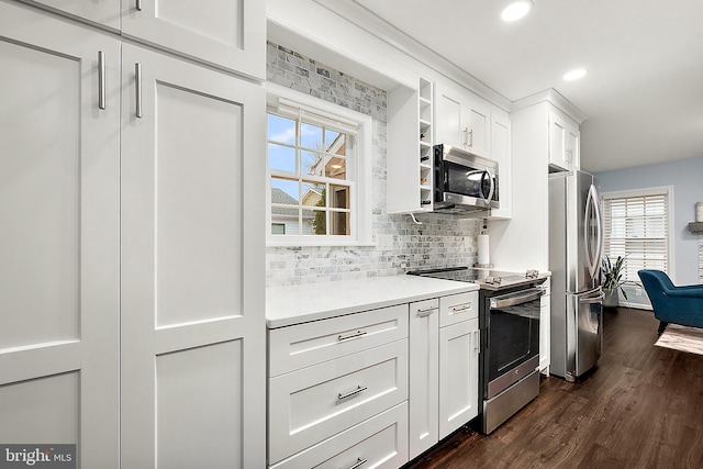 kitchen with appliances with stainless steel finishes, tasteful backsplash, white cabinetry, and dark wood-type flooring