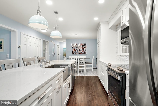 kitchen with backsplash, white cabinets, hanging light fixtures, dark hardwood / wood-style flooring, and stainless steel appliances