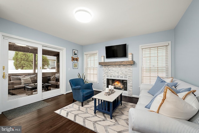 living room featuring wood-type flooring, a wealth of natural light, and a tiled fireplace