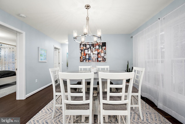 dining space with dark hardwood / wood-style floors and an inviting chandelier