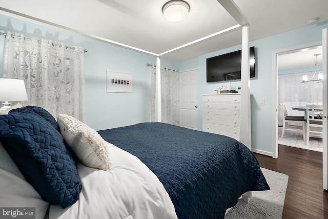 bedroom with dark hardwood / wood-style floors and a notable chandelier