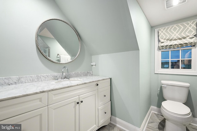 bathroom featuring vanity, toilet, and lofted ceiling