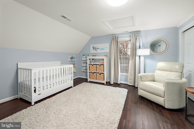 bedroom featuring dark hardwood / wood-style flooring, a nursery area, and lofted ceiling