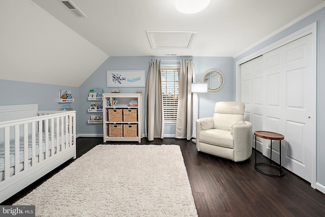 bedroom featuring dark hardwood / wood-style floors, a closet, a crib, and lofted ceiling