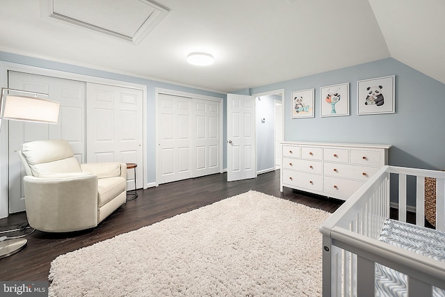 bedroom featuring dark hardwood / wood-style flooring, a crib, and vaulted ceiling