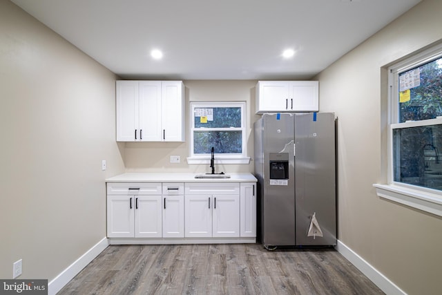 kitchen with stainless steel fridge, white cabinetry, sink, and a wealth of natural light