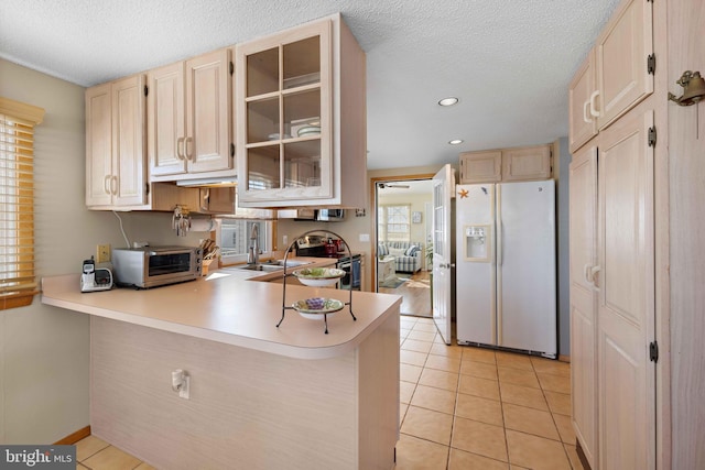 kitchen featuring kitchen peninsula, light tile patterned flooring, white fridge with ice dispenser, and stainless steel electric range