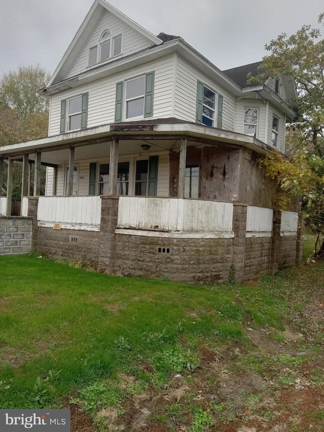 view of side of home with a porch and a yard