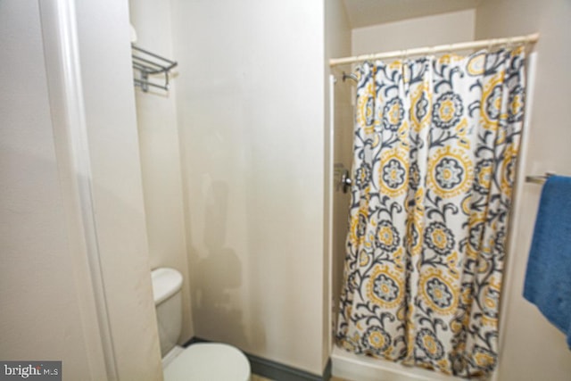 bathroom featuring a shower with curtain and toilet