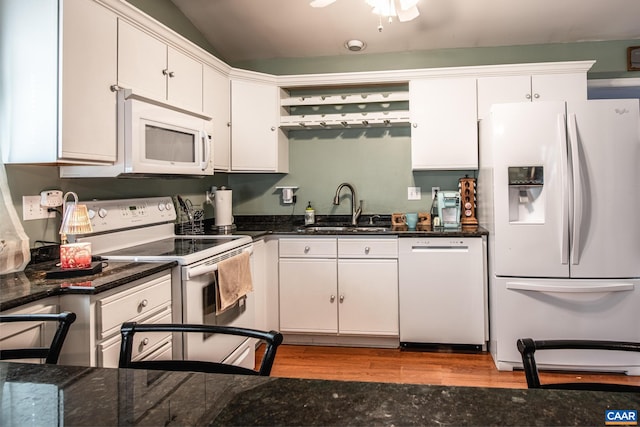 kitchen featuring white appliances, white cabinets, sink, vaulted ceiling, and light wood-type flooring