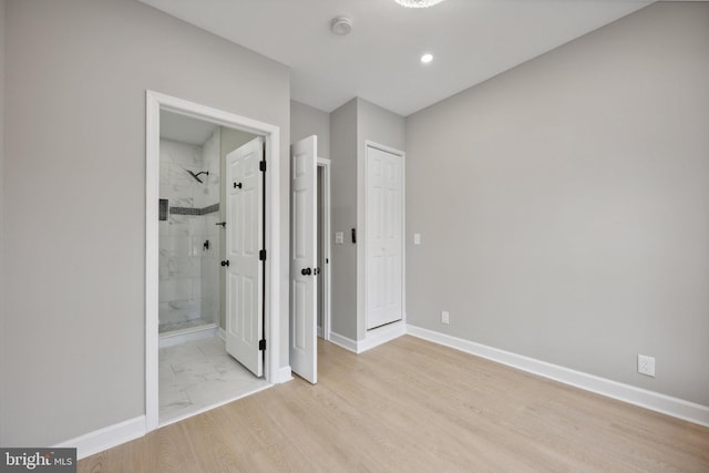unfurnished bedroom with ensuite bath and light wood-type flooring