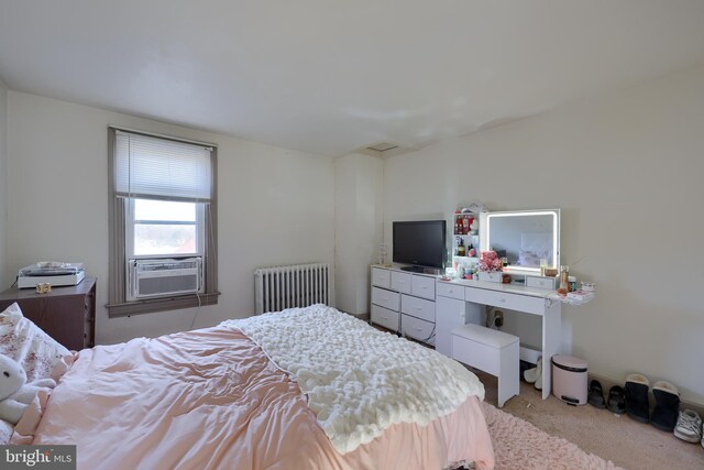 bedroom with radiator, cooling unit, and light colored carpet