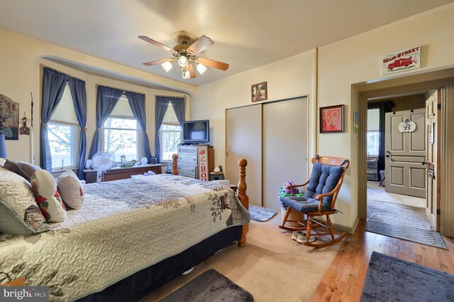 bedroom with ceiling fan, a closet, and light hardwood / wood-style floors