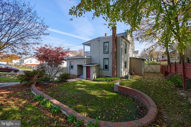 rear view of house with cooling unit and a lawn