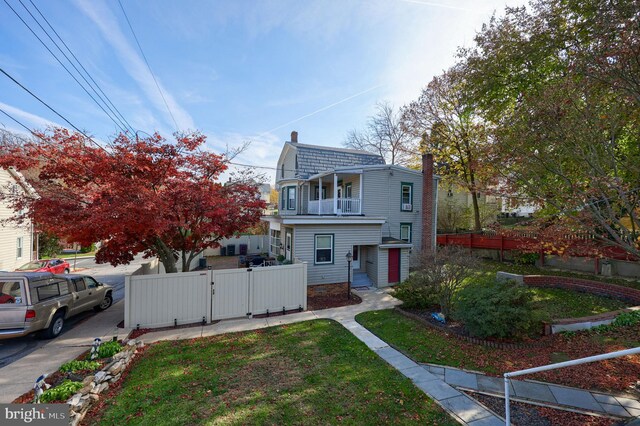 view of front of property featuring a balcony and a front lawn