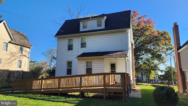 rear view of property with a deck and a lawn