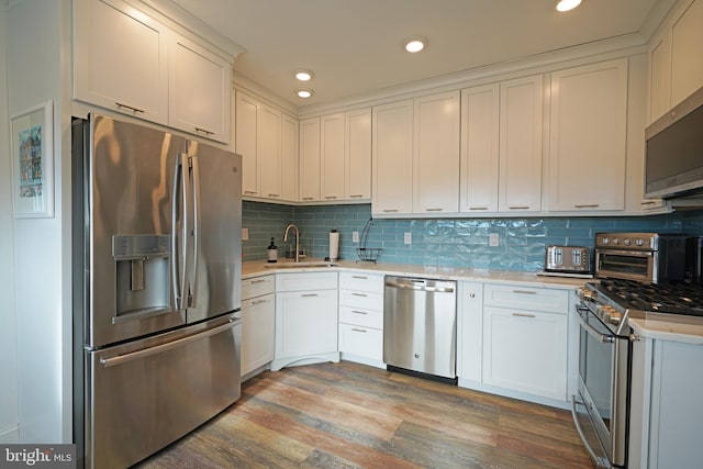 kitchen featuring tasteful backsplash, appliances with stainless steel finishes, light hardwood / wood-style floors, and white cabinets