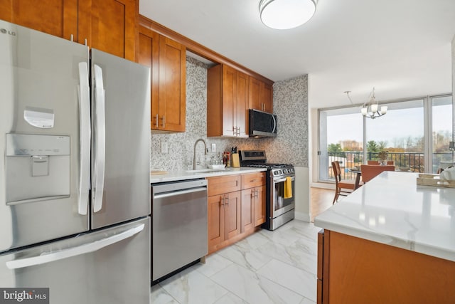 kitchen with appliances with stainless steel finishes, backsplash, sink, decorative light fixtures, and a notable chandelier