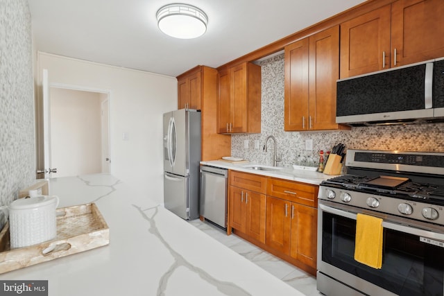 kitchen featuring appliances with stainless steel finishes, backsplash, light stone counters, and sink