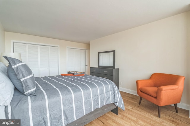 bedroom with two closets and light hardwood / wood-style floors