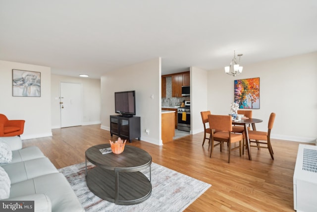 living room featuring sink, light hardwood / wood-style flooring, and an inviting chandelier