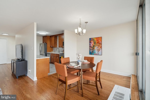 dining room featuring light wood-type flooring, sink, and an inviting chandelier