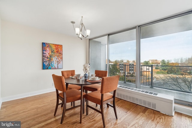 dining space featuring a notable chandelier, expansive windows, radiator heating unit, and light hardwood / wood-style flooring