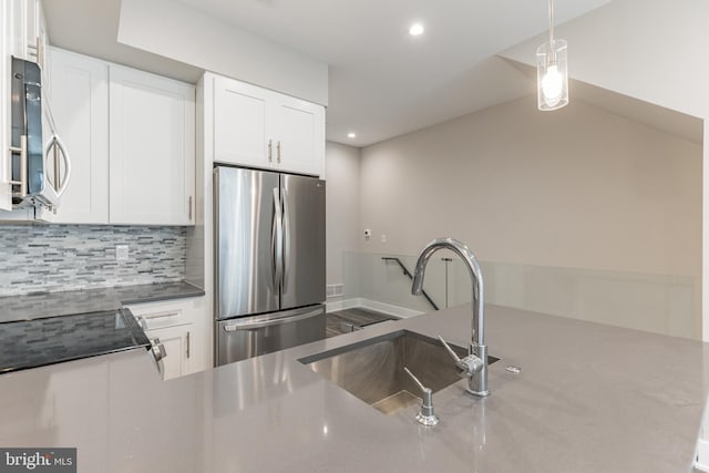 kitchen with white cabinets, sink, hanging light fixtures, appliances with stainless steel finishes, and tasteful backsplash