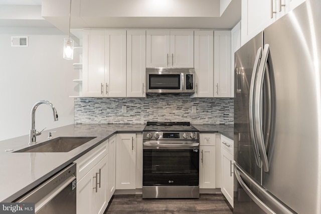 kitchen featuring sink, dark hardwood / wood-style floors, appliances with stainless steel finishes, decorative light fixtures, and white cabinetry