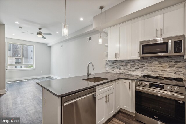 kitchen with white cabinetry, sink, stainless steel appliances, kitchen peninsula, and decorative light fixtures