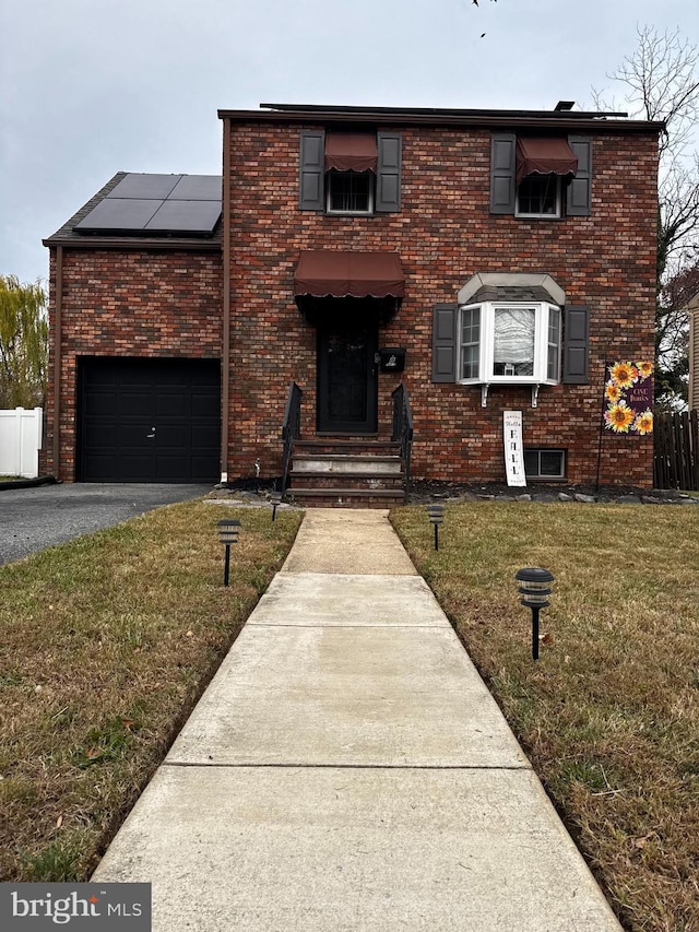 view of front of home with solar panels and a front lawn