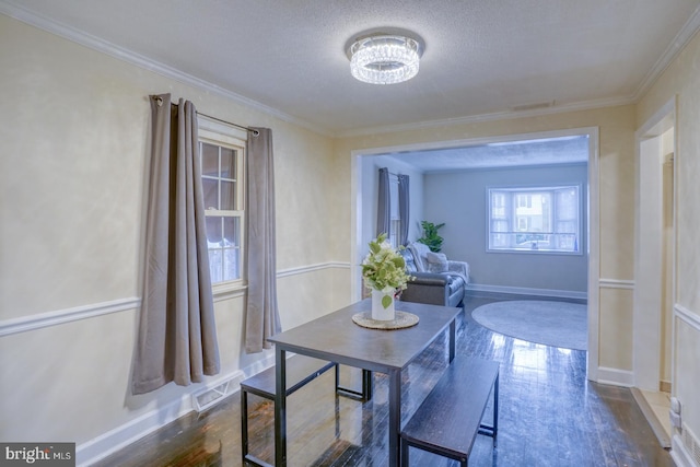 dining room featuring dark hardwood / wood-style flooring, a chandelier, a textured ceiling, and ornamental molding