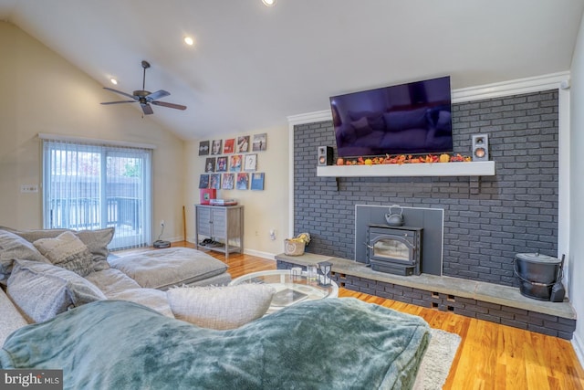 living room with wood-type flooring, vaulted ceiling, a wood stove, and ceiling fan