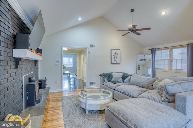 living room featuring a wood stove, plenty of natural light, brick wall, and hardwood / wood-style flooring