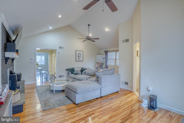 living room featuring plenty of natural light, high vaulted ceiling, and light hardwood / wood-style flooring