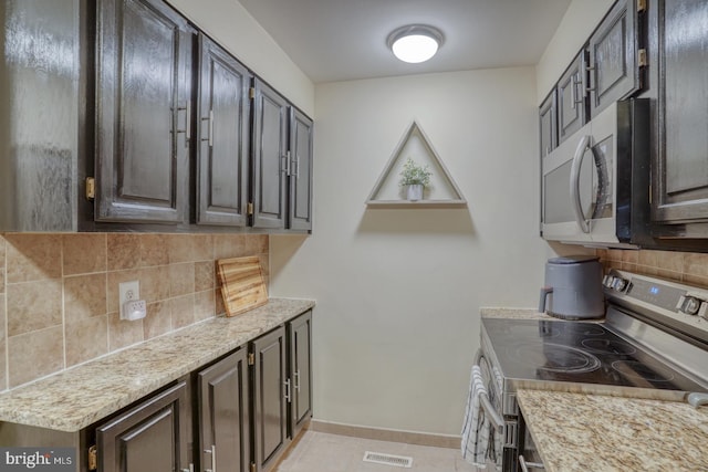 kitchen featuring tasteful backsplash, dark brown cabinetry, and appliances with stainless steel finishes