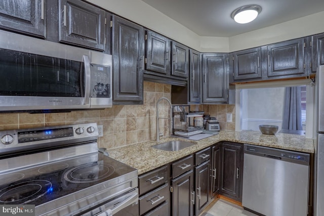 kitchen featuring sink, tasteful backsplash, light tile patterned flooring, light stone counters, and stainless steel appliances