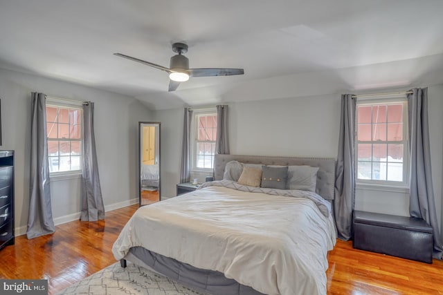 bedroom featuring ceiling fan, lofted ceiling, light wood-type flooring, and multiple windows