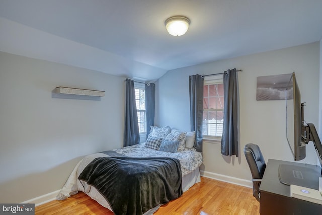 bedroom with light wood-type flooring and vaulted ceiling