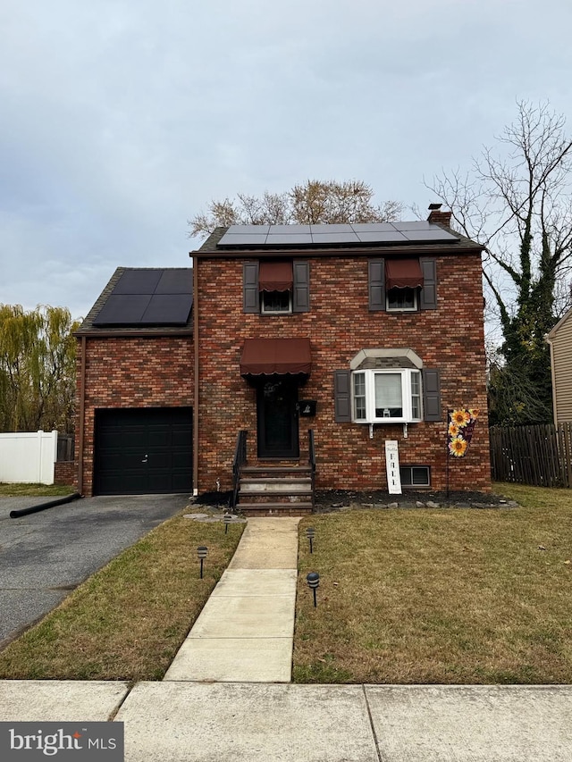 front facade with solar panels, a garage, and a front lawn