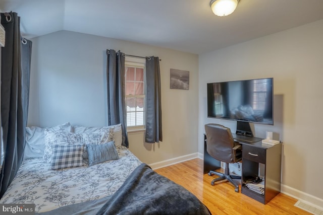 bedroom with light wood-type flooring and vaulted ceiling