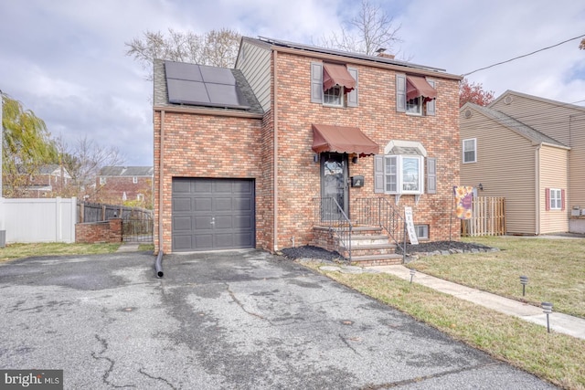 view of front of home featuring a front yard, solar panels, and a garage