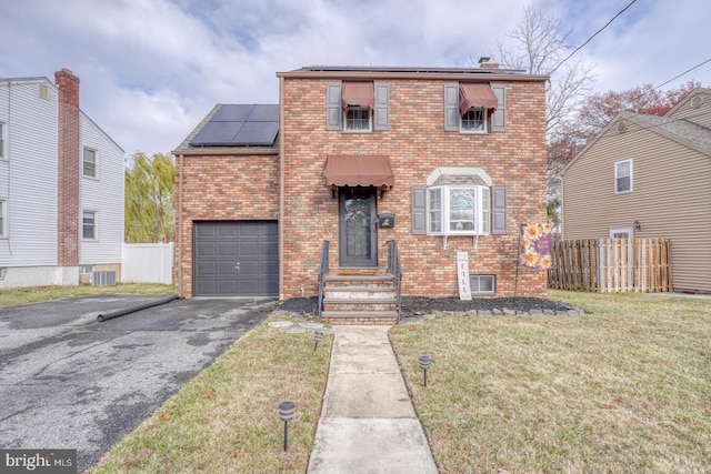 view of front property featuring solar panels, a garage, and a front yard