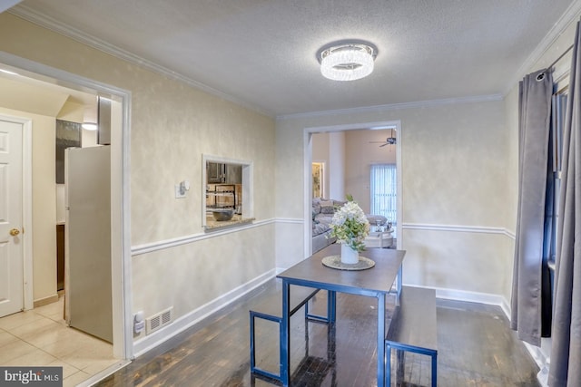 dining room with wood-type flooring, a textured ceiling, ceiling fan, and crown molding