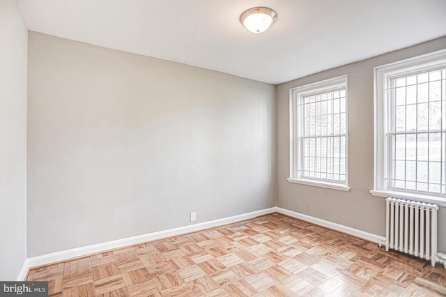 spare room featuring radiator and light parquet flooring