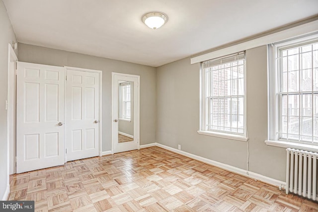 unfurnished bedroom featuring radiator heating unit and light parquet floors