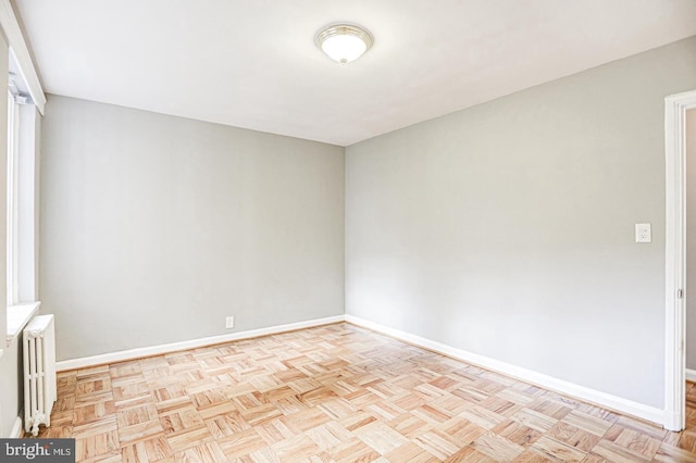 empty room with light parquet floors and radiator